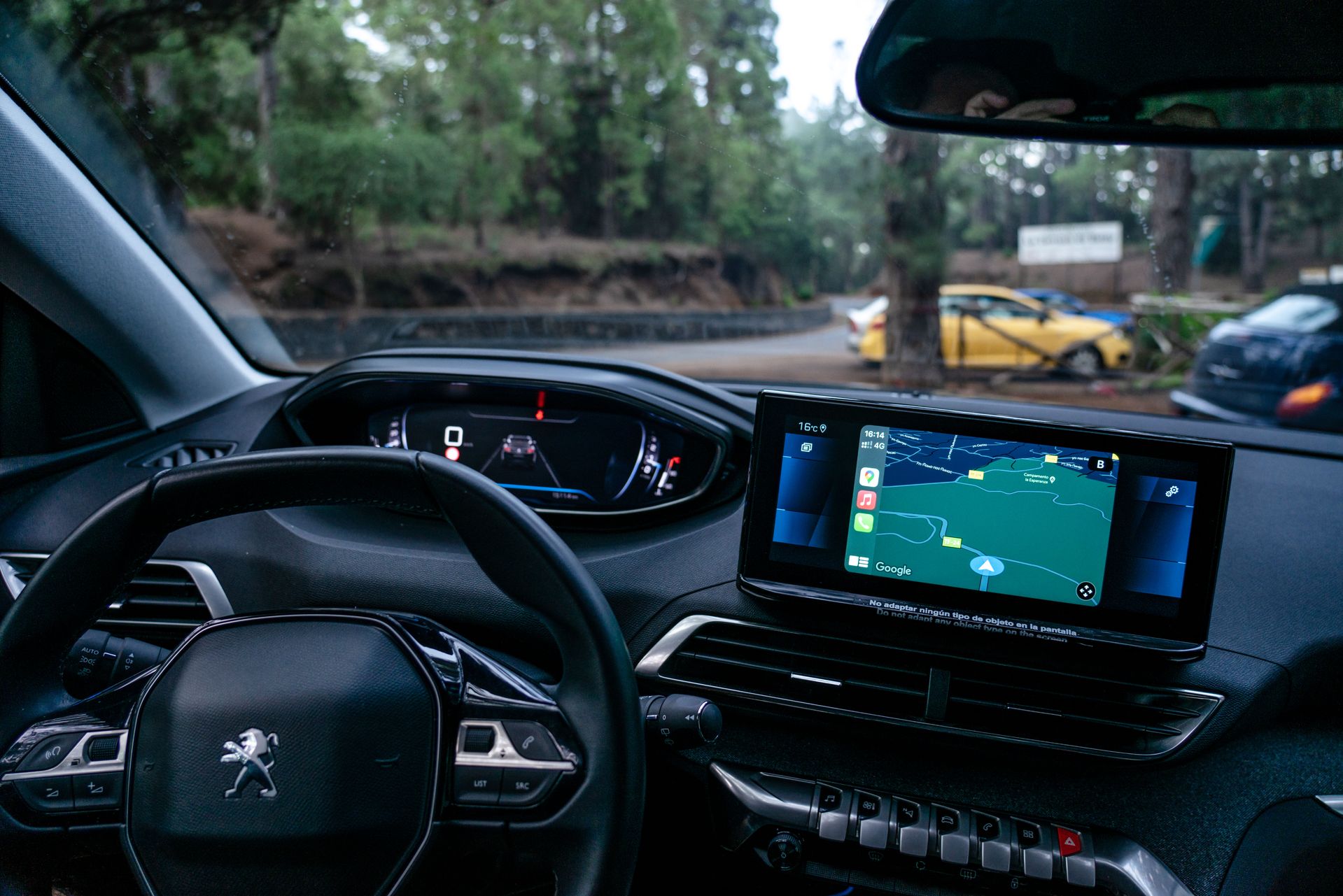 Habitacle d'une Peugeot 208 d'auto-école, volant et tableau de bord, route forestière au pare-brise